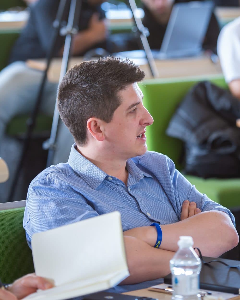 Alex Ford seated with a notebook, listening intently during a pitch