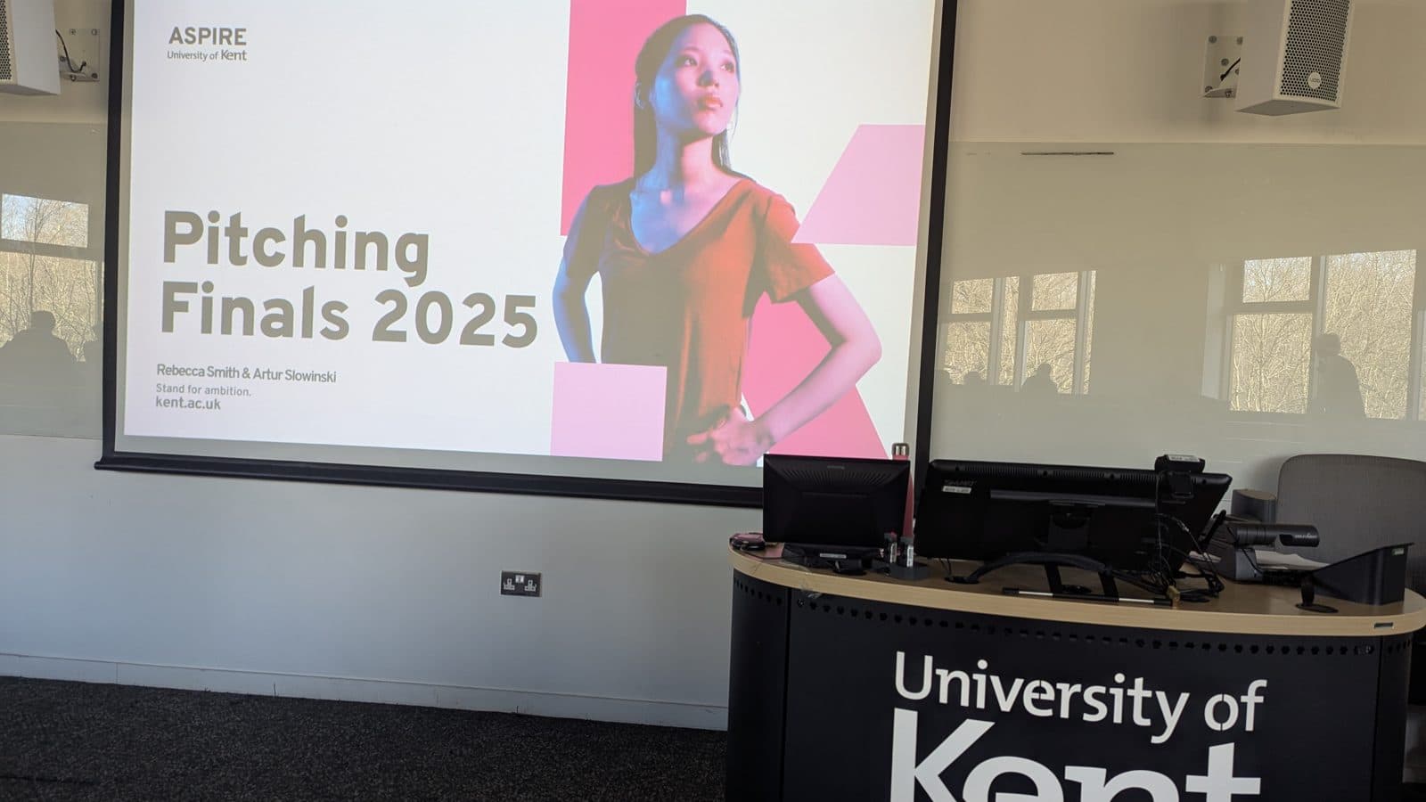 A lecture-room screen showing "ASPIRE Pitching Finals 2025" above a University of Kent lectern